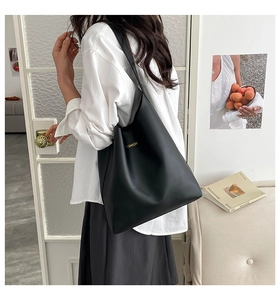 Mannequin portant un grand sac cabas noir hobo avec texte doré dans une pièce lumineuse