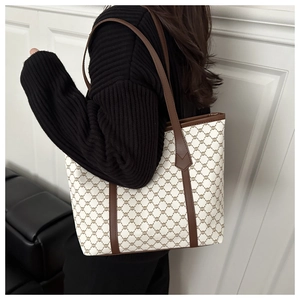Detail of vintage patterned tote bag with brown leather strap worn over the shoulder