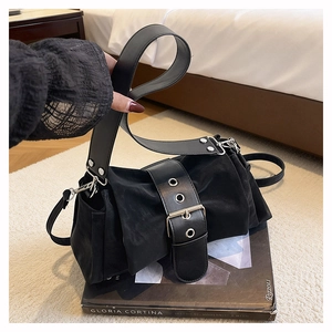 Détail d'un sac à bandoulière en tissu plissé noir avec boucles à œillets et sangle cuir