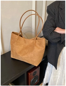 Dettaglio di una grande borsa tote in pelle scamosciata marrone con lunghi manici sottili