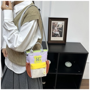 Detail of color-block pixel-style canvas bag with adjustable strap and yellow zipper pocket