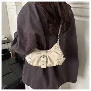 Detail view of cream crescent bag with silver metallic buckles and side rivets on model