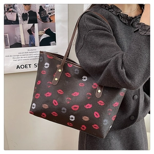 Close-up of a large brown tote bag with colorful lip prints worn on a woman's shoulder
