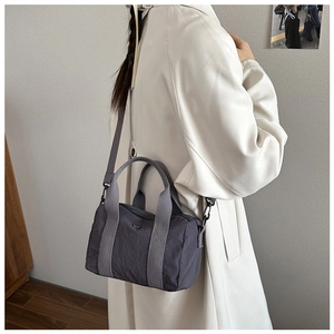 Lifestyle shot showing a multi-pocket grey nylon crossbody bag with wide shoulder strap