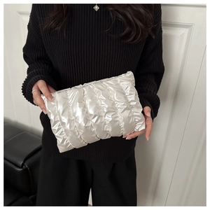 Detail of white quilted cloud pouch with pearl sheen finish held by a model