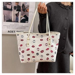Detail of cream tote bag featuring red lip prints and secure golden metal rivets