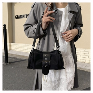 Détail d'un sac d'épaule en nylon noir avec large sangle en cuir et boucle argentée