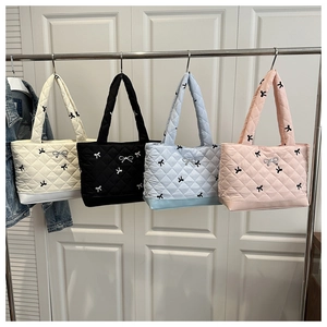 Detailed macro view of quilted tote bags in four colors with ribbon pattern and silver bow