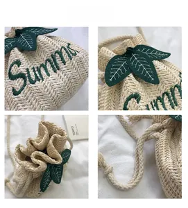 Detail of straw bucket bag with green Summer embroidery and drawstring closure