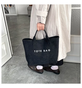 Minimalist black tote bag with white TOTE BAG lettering and long shoulder handles