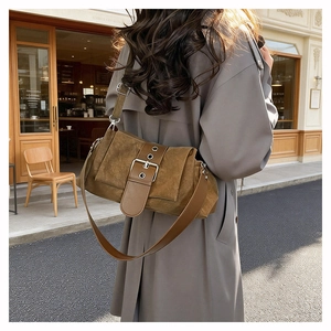 Détail d'un sac bandoulière en daim marron avec une boucle de ceinture argentée chic