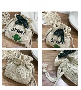Detail view of woven straw bucket bag featuring green leaf charms and cactus embroidery