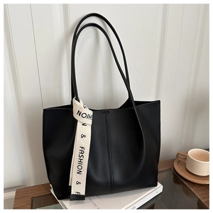 Detail of minimalist black leather tote bag with fashion ribbon and long shoulder straps