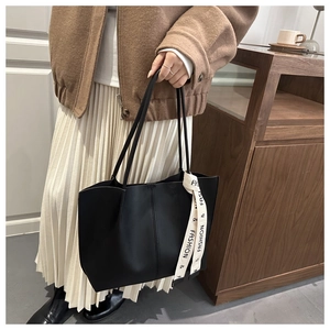 Dettaglio borsa tote nera in ecopelle con nastro decorativo e cuciture a contrasto