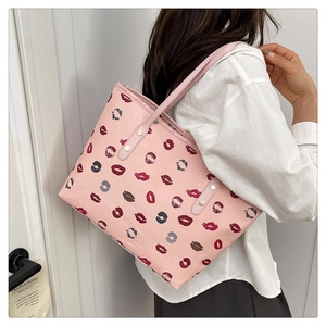 Detail of pink tote bag with red lip print pattern and silver rivet shoulder strap