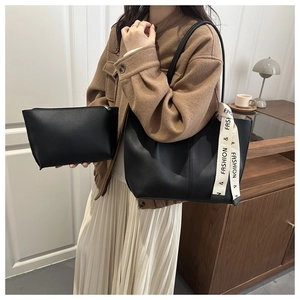 Detail of black leather tote bag set with a stylish fashion ribbon on the shoulder strap