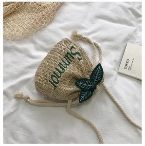Detailed straw bucket bag with Summer embroidery, green leaf accents and cotton drawstring