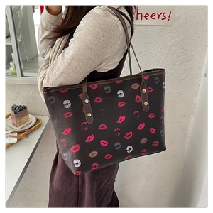 Detail of dark brown tote bag with colorful lip prints and gold rivet accents on strap