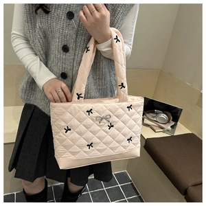 Detail of pink quilted tote bag with black bow embroidery and silver ribbon charm