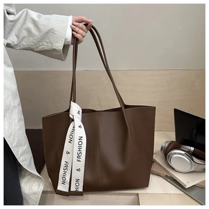 Detail of coffee brown large tote bag with white printed ribbon in an office setting