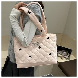 Detail of pink quilted tote bag with black bow embroidery and silver metallic bow accent