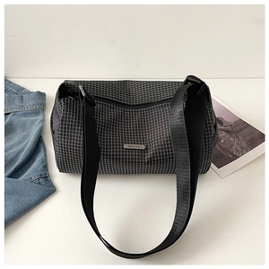 Détail du sac cylindrique en nylon noir à carreaux avec logo en métal et sangle