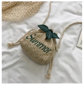 Detail of hand-woven straw bucket bag with Summer embroidery and green leaf accents