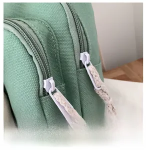 Gros plan du sac en toile vert menthe avec doubles fermetures éclair et tirettes en corde blanche