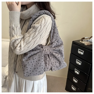 Detailopname van de grijze corduroy hobo-tas met bloemenpatronen en een grote strik