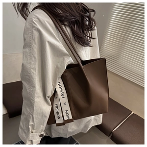 Dettaglio della grande borsa tote marrone con tracolla a contrasto e scritta fashion