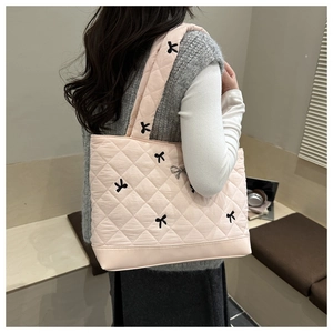 Pink quilted tote bag detail with black bow embroidery and silver metallic bow charm