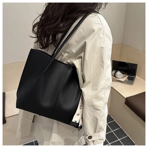 Detail of minimalist black leather tote bag with stylish white lettered strap on the side