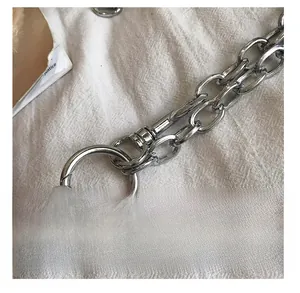 Close-up of polished silver metal chain hook and spring ring on white fabric