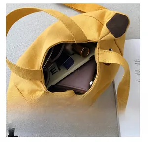 Intérieur spacieux du sac en toile jaune montrant la capacité pour portefeuille et produits