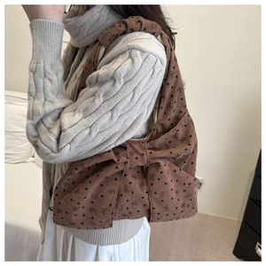 Detailansicht einer braunen Cord-Tasche mit großer Schleife und Herz-Prints an der Schulter