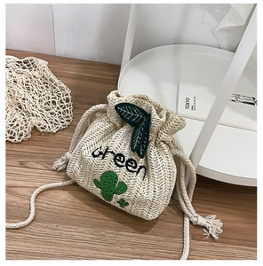 Detail of straw woven bucket bag with green cactus embroidery and leaf drawstring tie