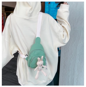 Détail du sac de poitrine en toile vert fruit avec bandoulière large et charme lapin en peluche