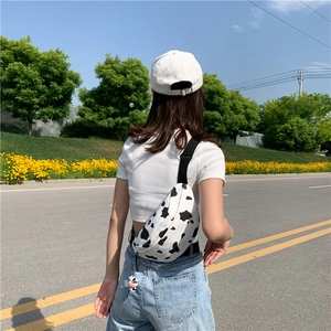 Outdoor shot of cow print canvas fanny pack with adjustable strap and cute cow charm