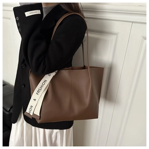 Detail of minimalist brown large tote bag with a white fashion ribbon on the strap