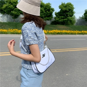 Detailed view of white fabric shoulder bag featuring black planet embroidery and silver chain