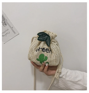 Detail of straw bucket bag featuring green cactus embroidery and leaf drawstrings