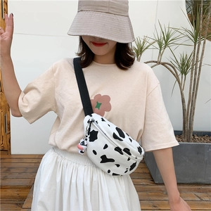 Detail of cow print canvas crossbody bag with adjustable strap and plush cow charm