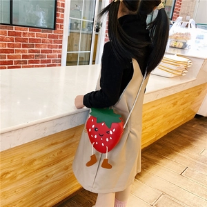 Detail of red strawberry crossbody bag for girls with cute cartoon face and leaf design