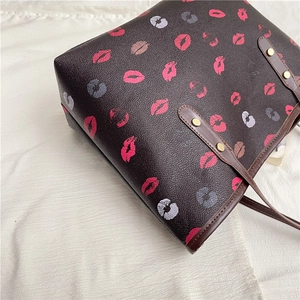 Large dark brown leather tote bag with colorful lip prints and gold rivets on shoulder strap