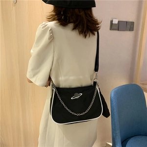 Detail of black nylon baguette bag featuring white piping and silver planet logo