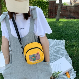 Détail du sac bandoulière en toile jaune avec motif de monstre et sangle ajustable