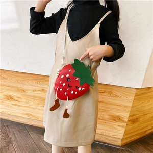 Detail of red strawberry girls crossbody bag with cute cartoon face and leaf decor