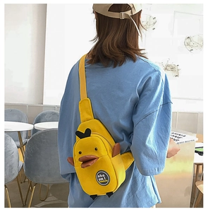 Detail view of a yellow cartoon duck canvas crossbody bag with adjustable straps on model