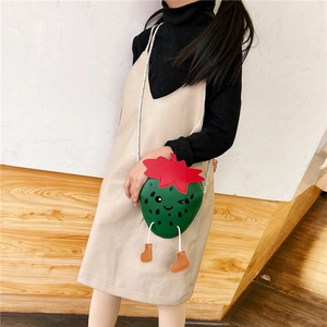 Kid's strawberry shaped crossbody bag in green PU leather worn by a child model