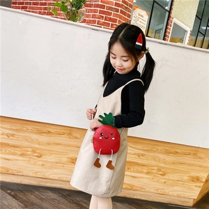 Détail du sac bandoulière ananas rouge mignon avec visage de dessin animé porté par une fille